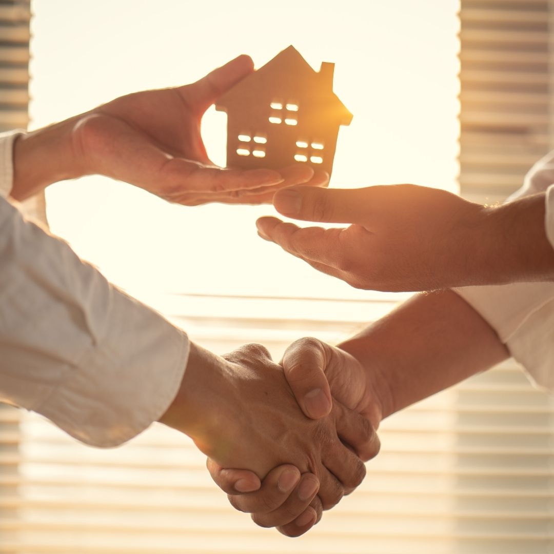 Shaking hands and handing over a small model house