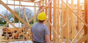 man in hard hat looks at framing in a new construction house