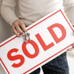 Person holding a "Sold" sign