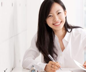 Young woman studying for the Pearson Vue real estate exam with textbook and laptop
