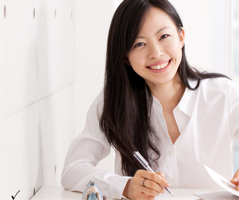 Young woman studying for the Pearson Vue real estate exam with textbook and laptop